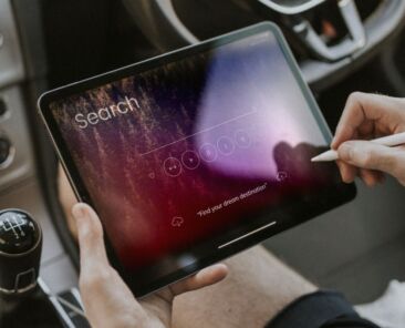 Hand holding stylus pen searching on a tablet in a car